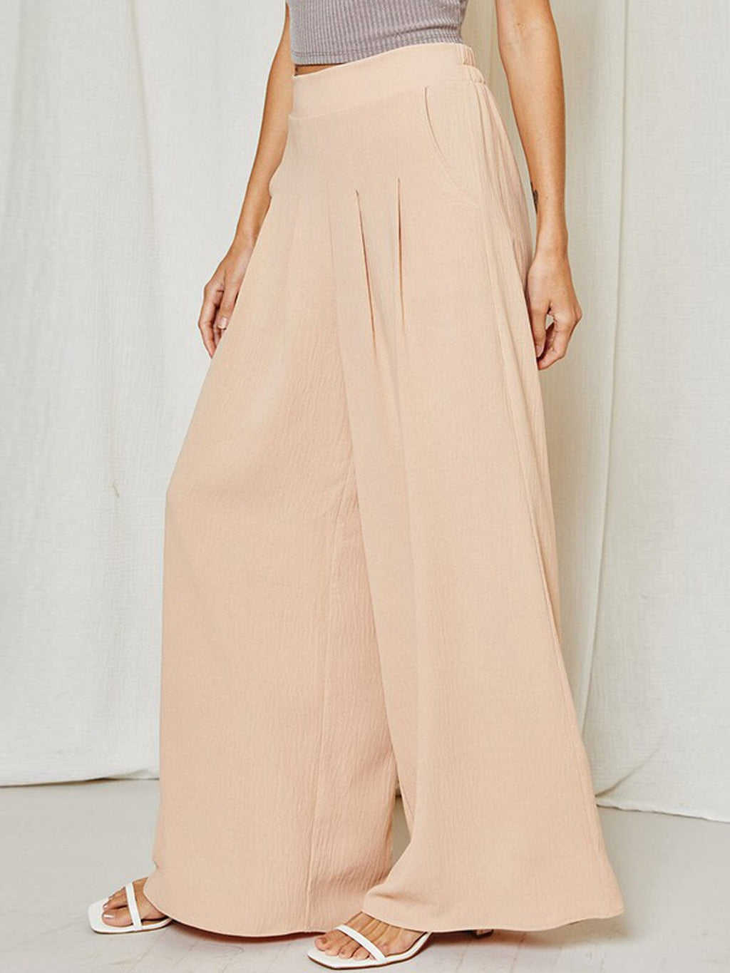 Detail of pleated wide leg trousers in soft taupe