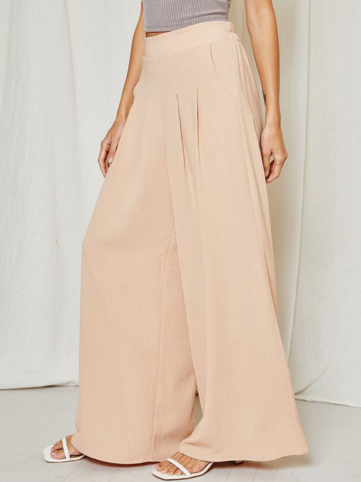Detail of pleated wide leg trousers in soft taupe